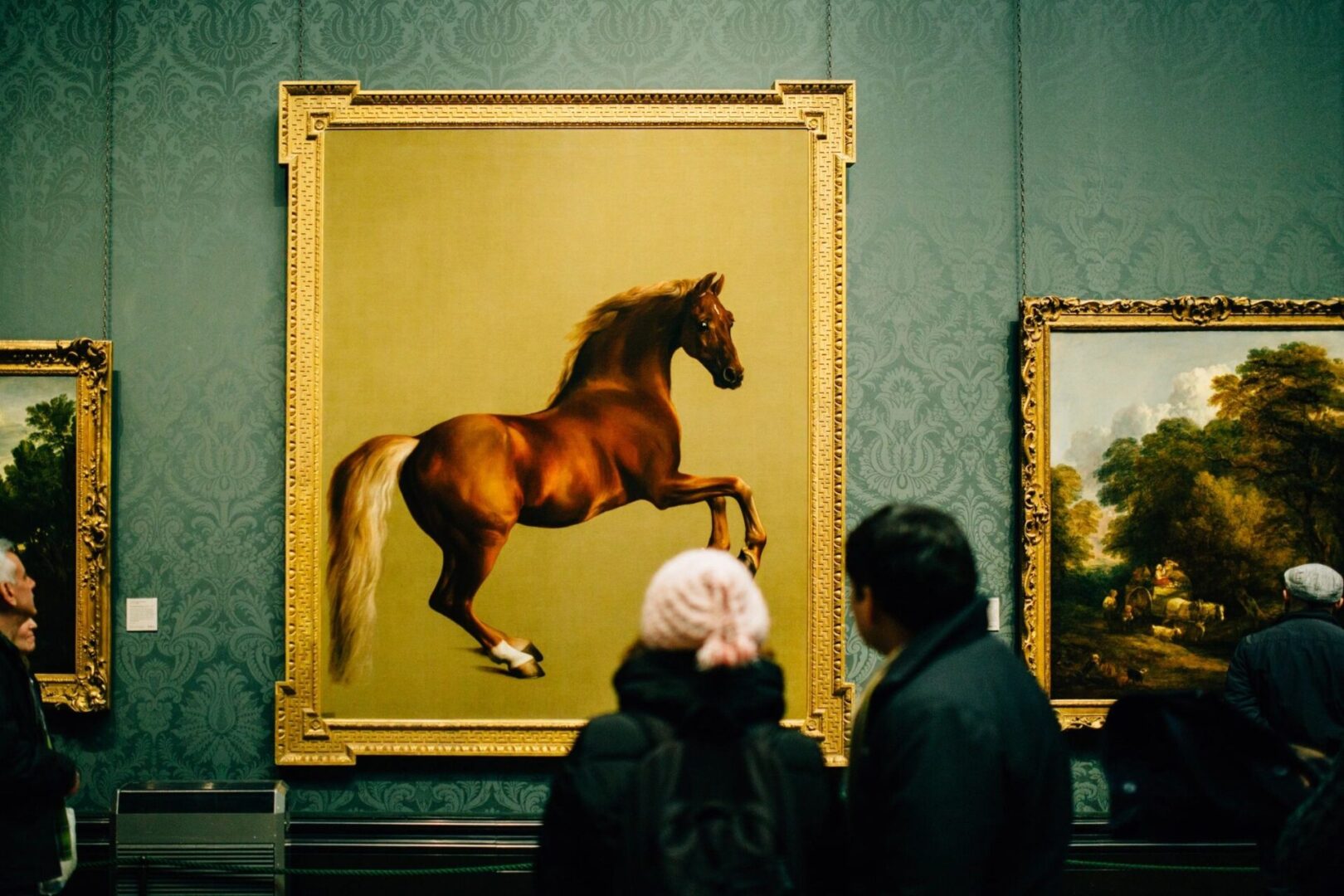 Two people looking at a painting of a horse.