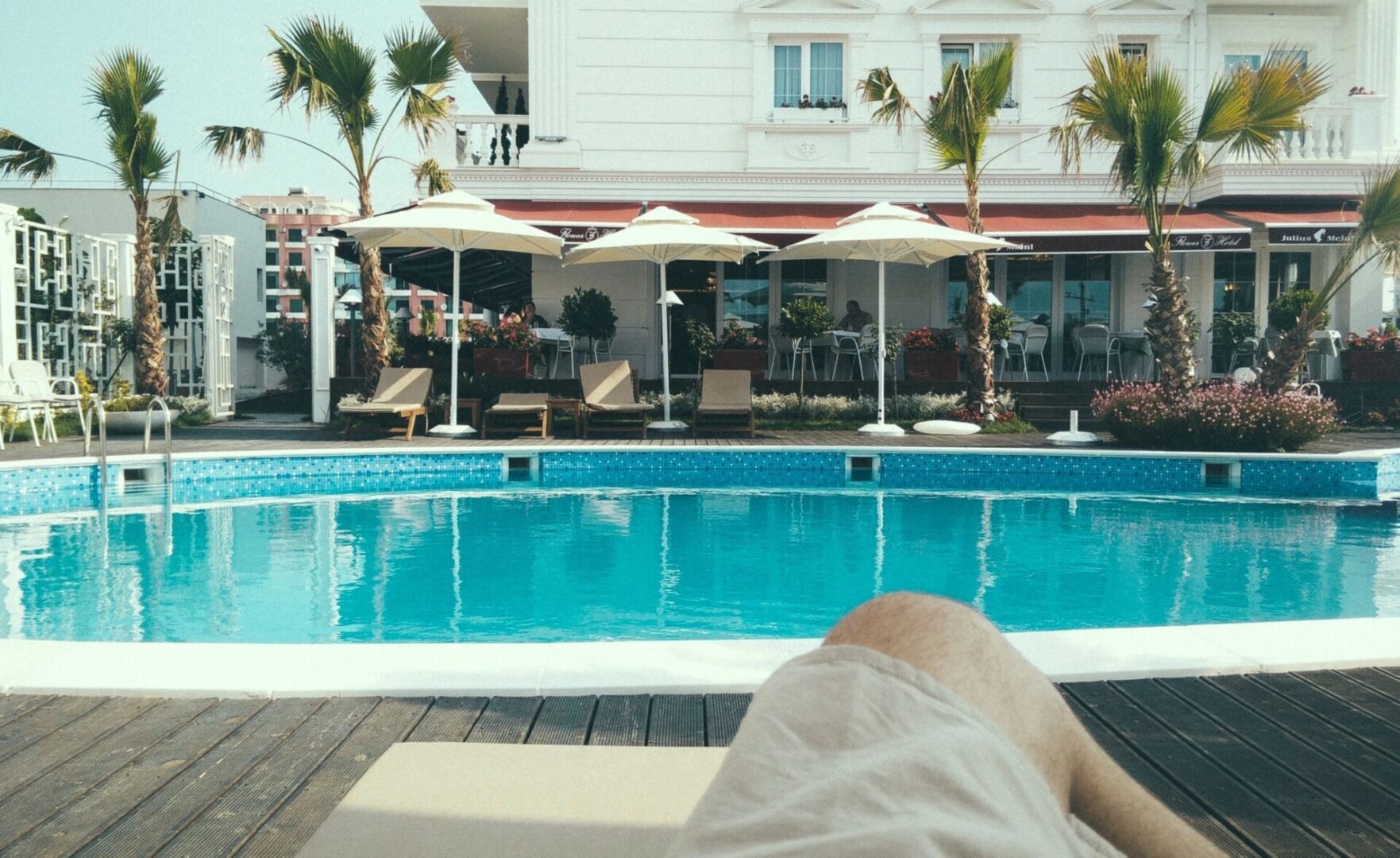 A person laying on the ground near an outdoor pool.