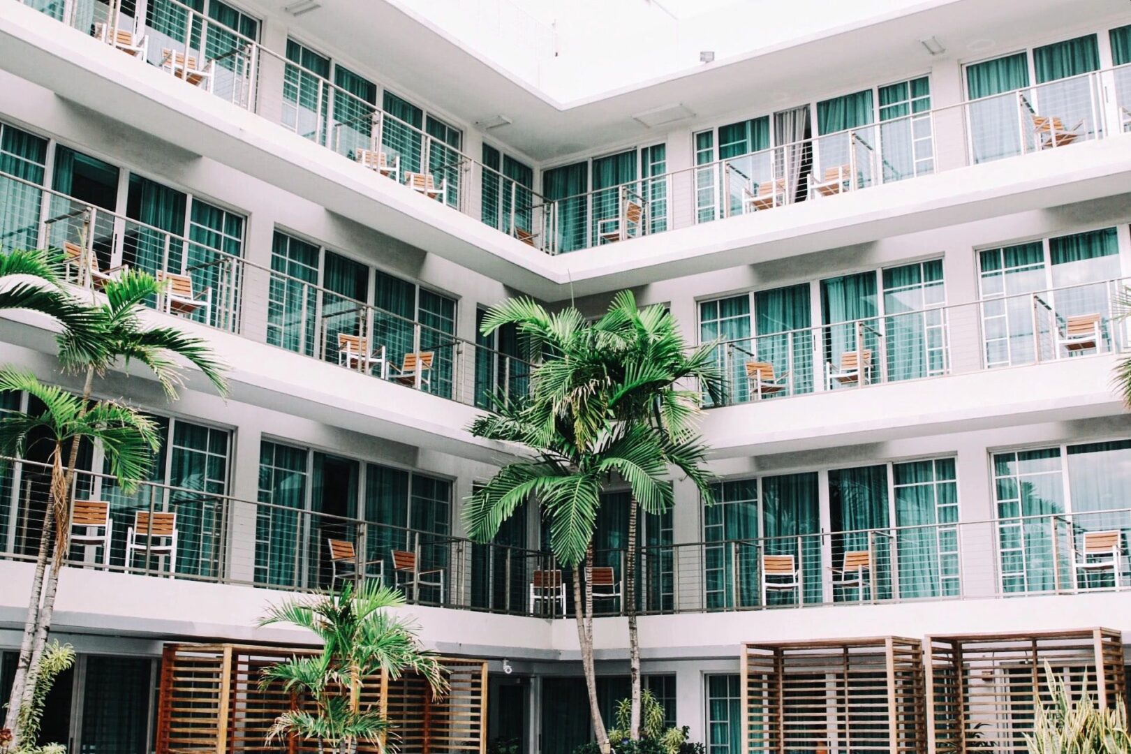 A building with many windows and palm trees in the corner.