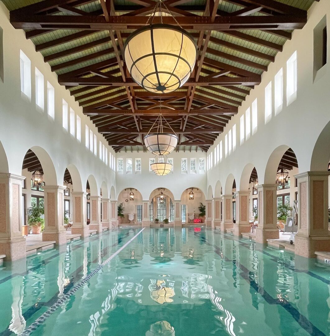 A large indoor swimming pool with arches and columns.