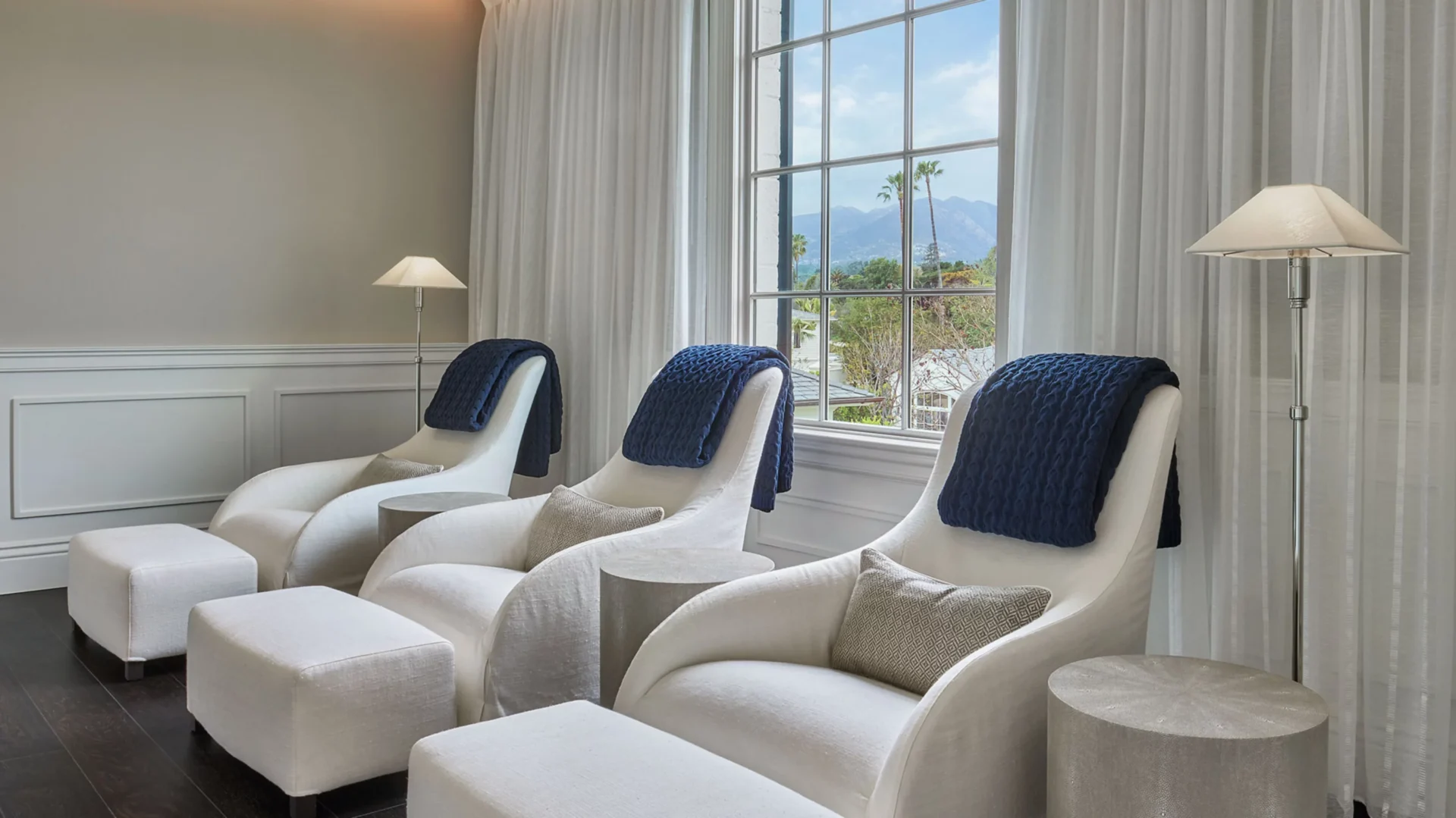 A row of white chairs in front of a window.