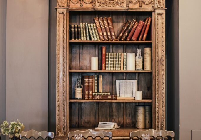 A wooden table with chairs and a book shelf.